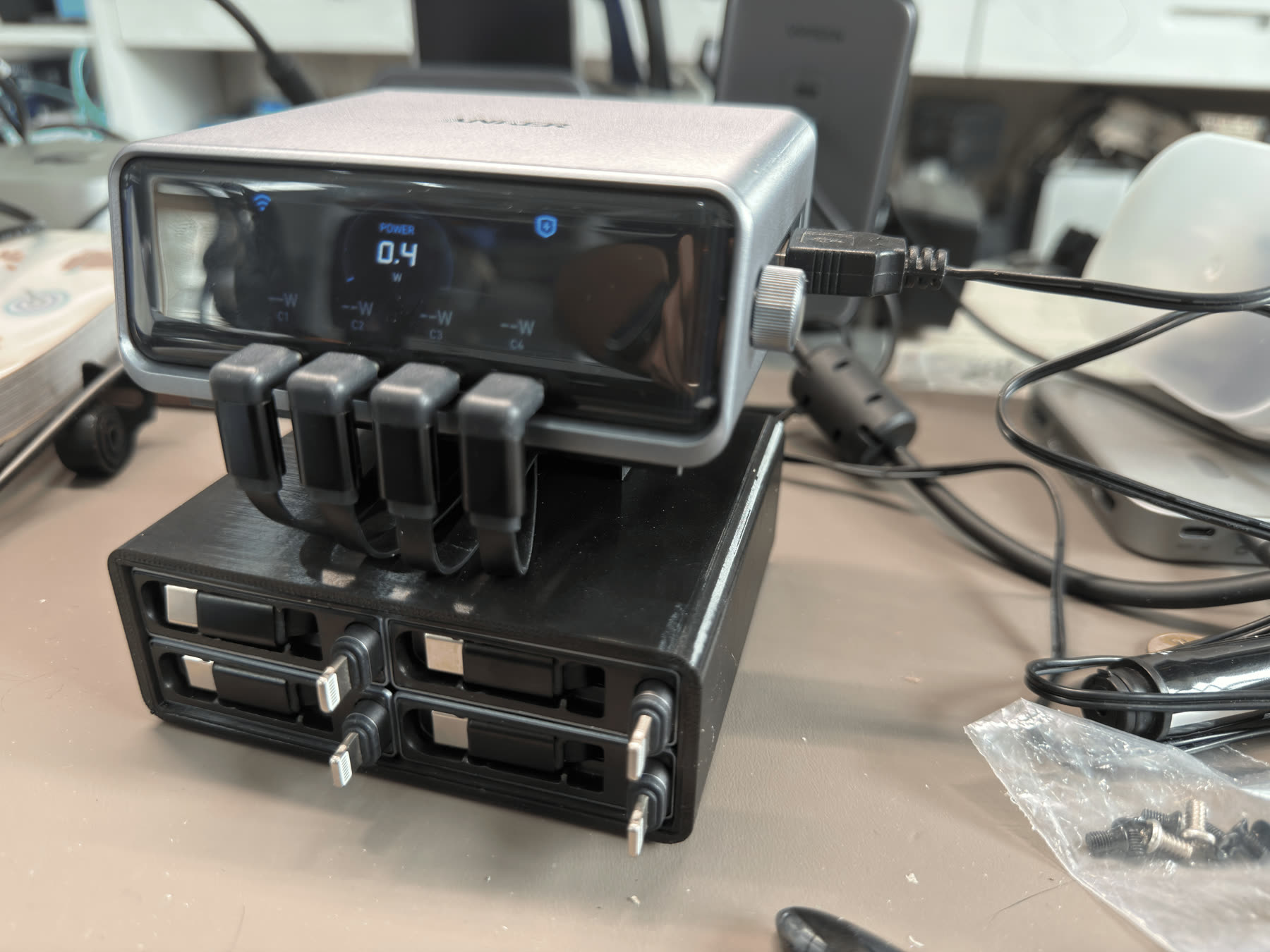 An Anker Prime 250W charger sitting on a black 3D printed base with four modular retractable cables.